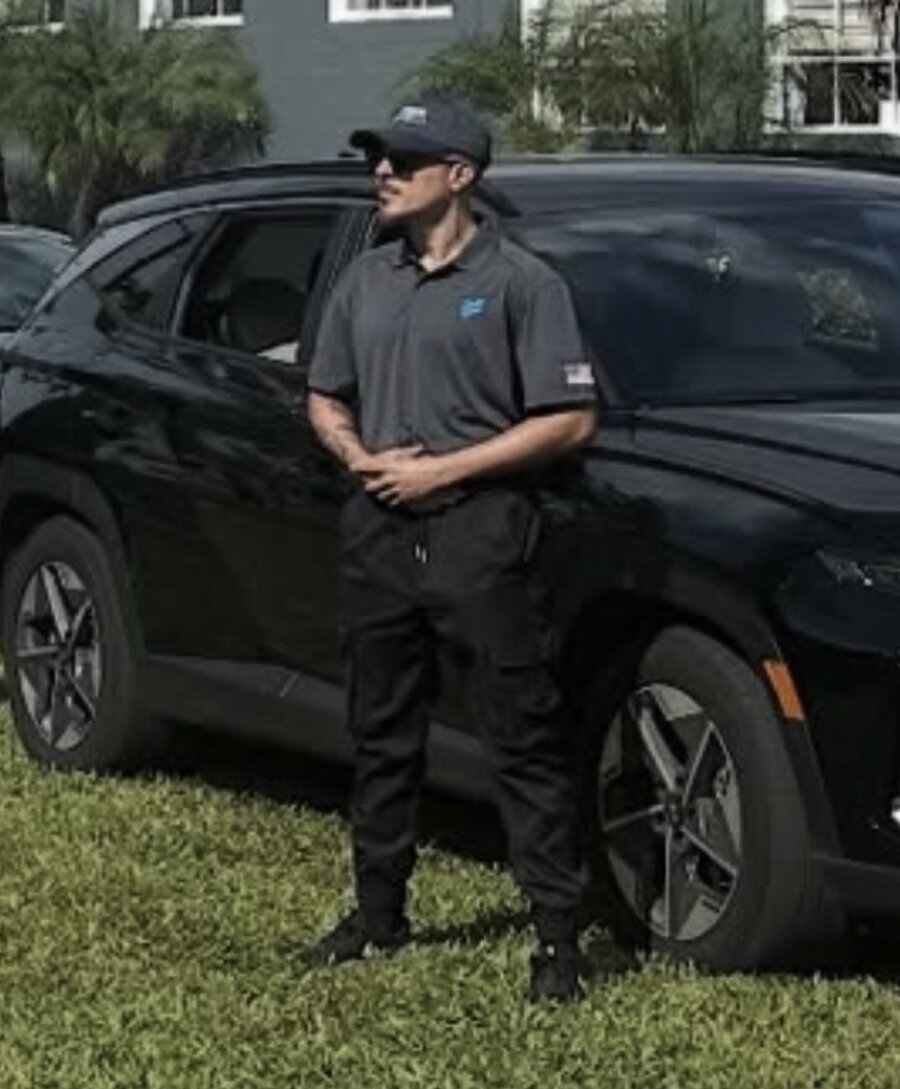 Devin Fred standing post beside a black SUV during ESS Academy training